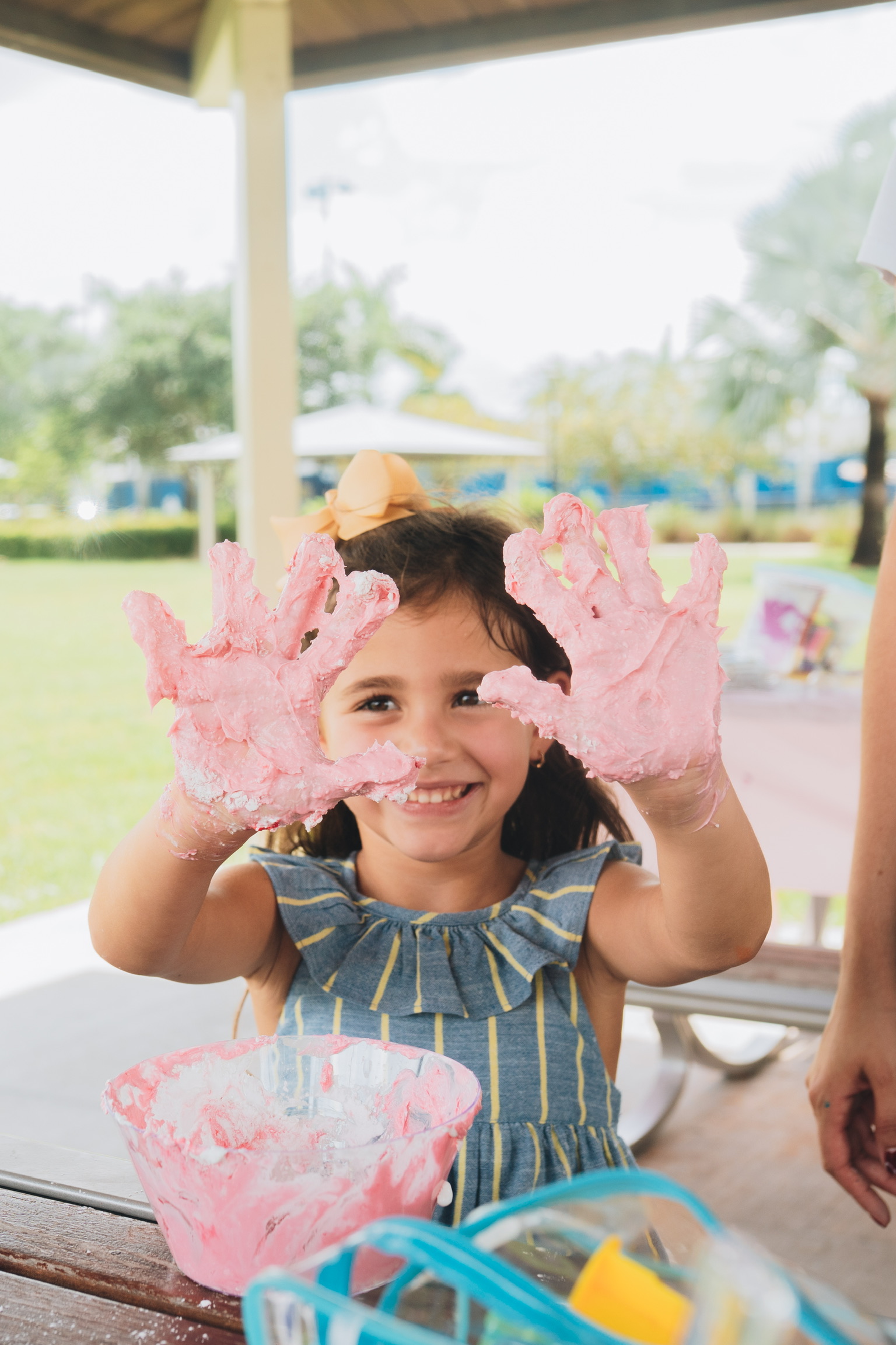 A child smiling with colorful sensory foam on their hands