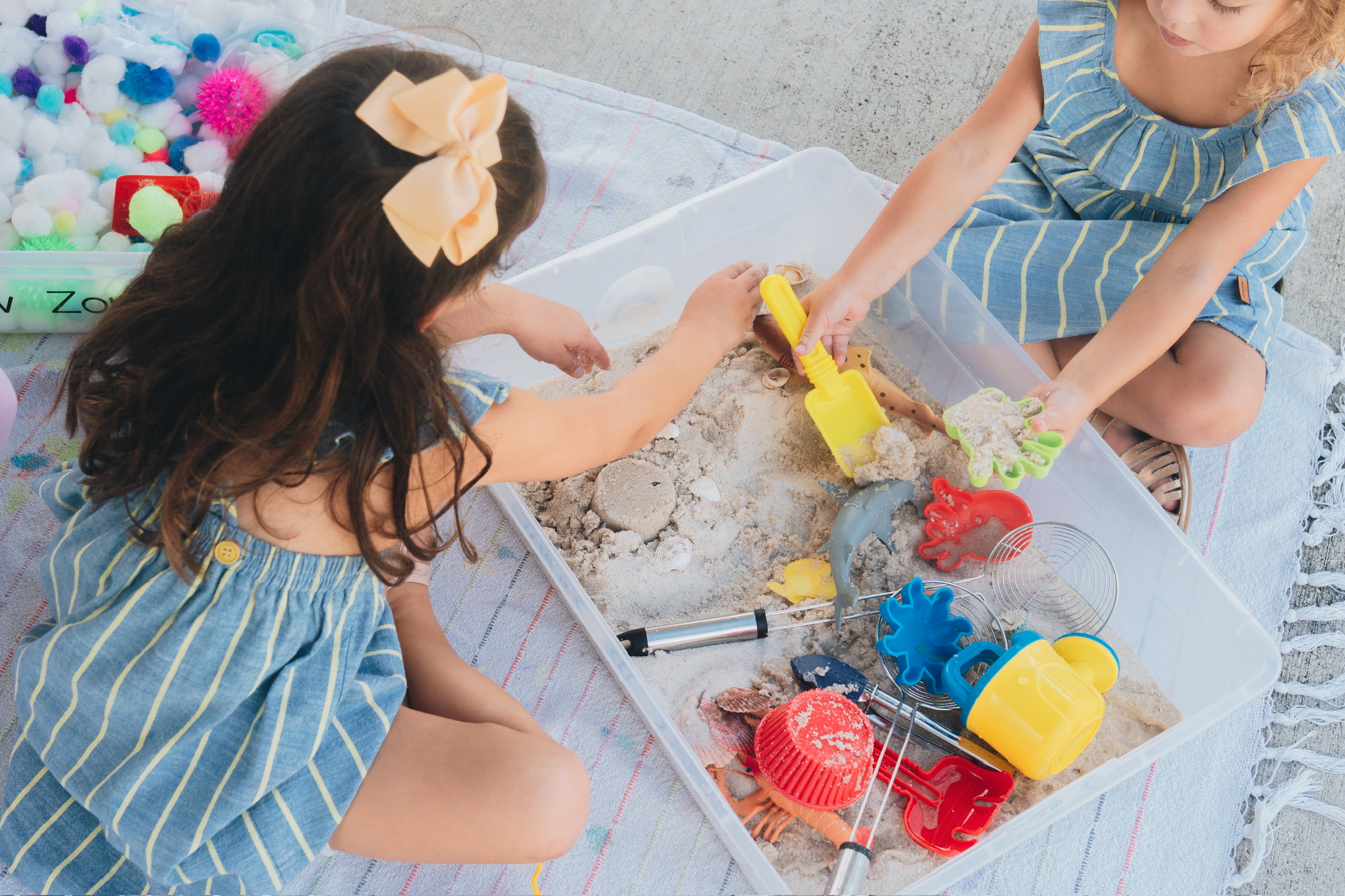Two children playing in a sand sensory bin